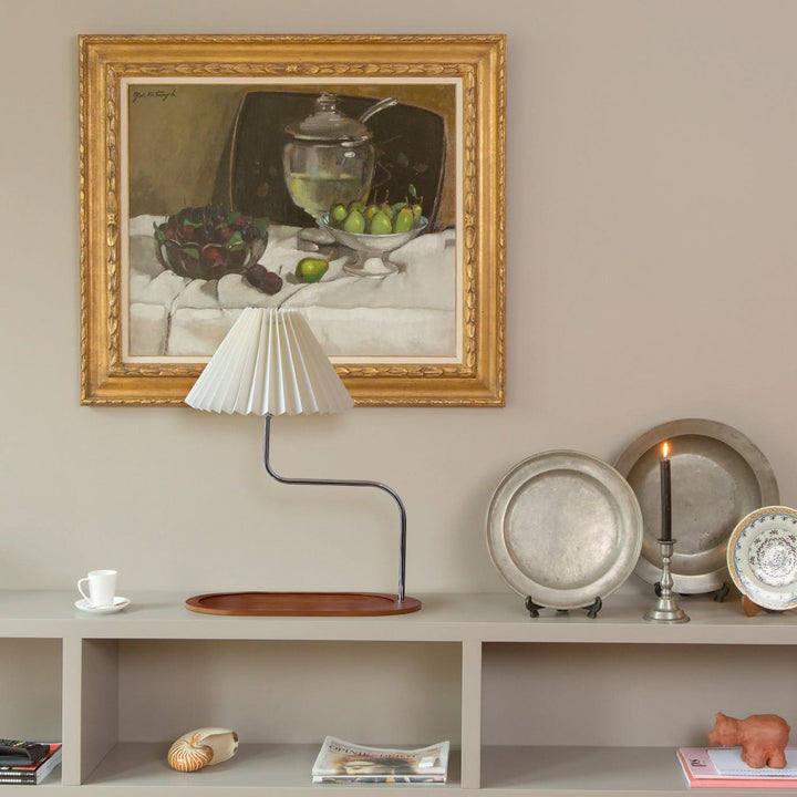 Beige pleated table lamp on bedside table with books on tray base